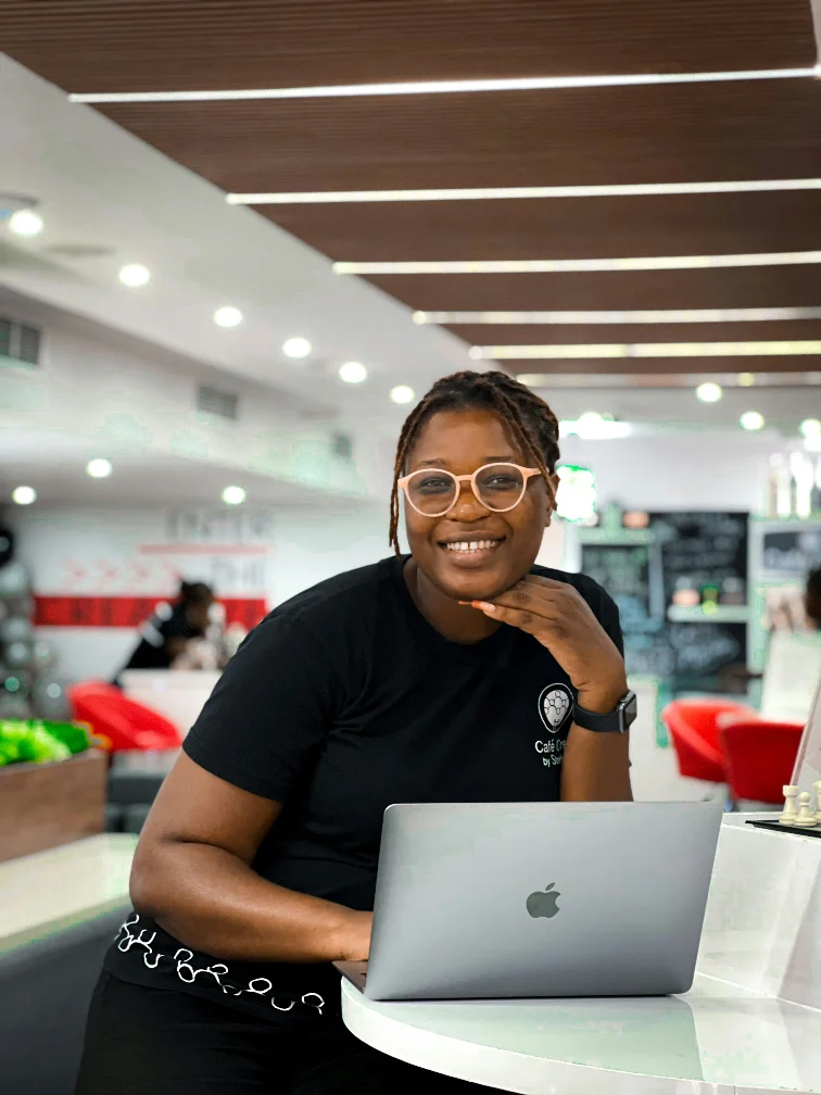 A smiling product professional working at a laptop in a café