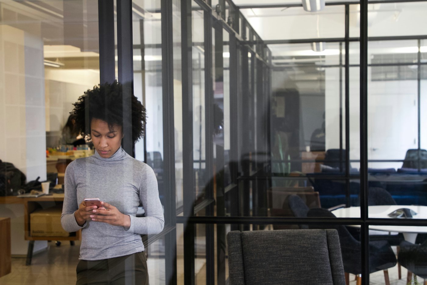 A product marketer checking her phone in a glass-walled office