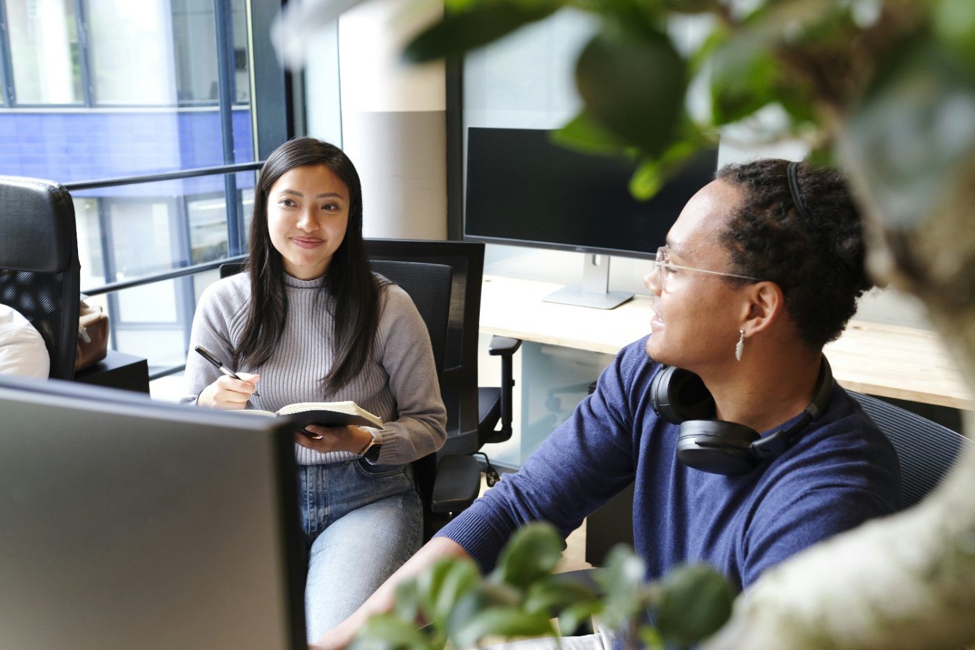 Two product marketers talking through a plan at their desks